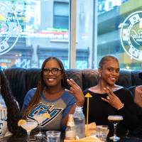 Group of event attendees sitting in booth and smiling for camera